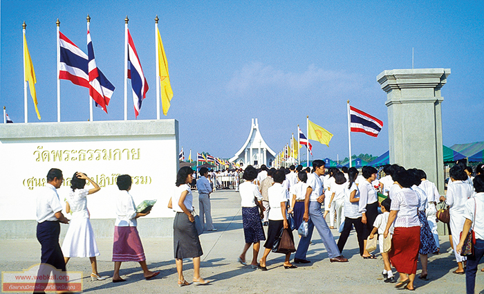 สาธุชนเดินเข้าประตูหน้าวัดพระธรรมกาย เพื่อมาร่วมงานวันมาฆบูชา ในวันที่ ๘ กุมภาพันธ์ พ.ศ. ๒๕๒๕ เมื่อ ๓๖ ปีที่ผ่านมา